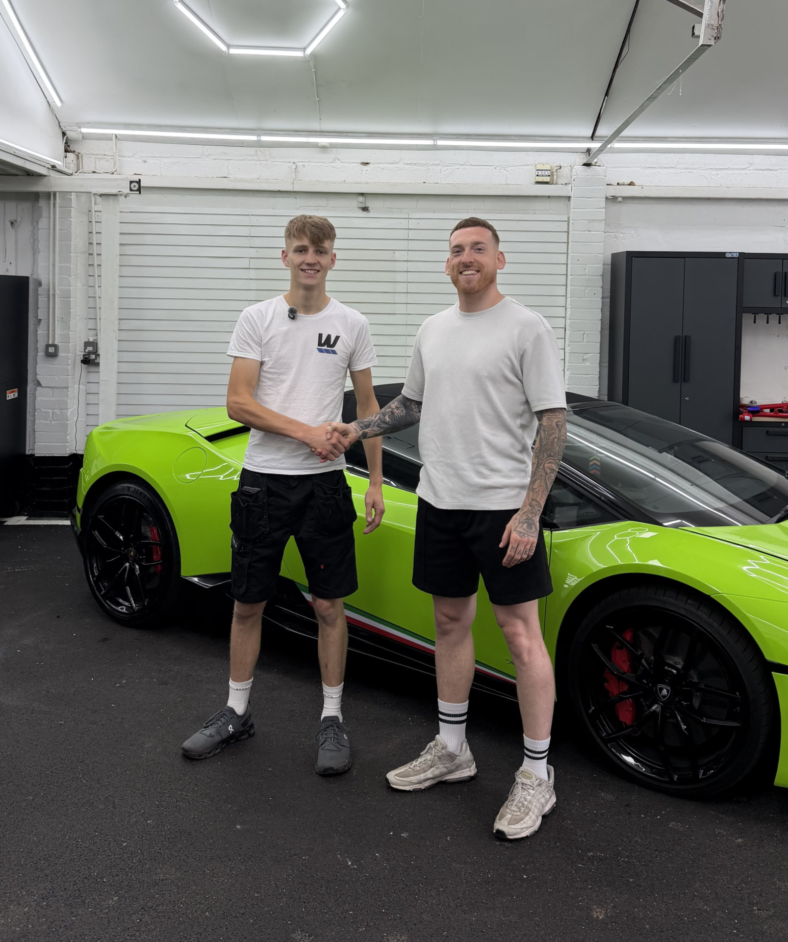 Two of the team standing in front of a lime green vinyl wrapped car outside the workshop